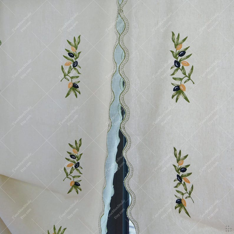 May include: Off-white fabric with embroidered olive branches featuring green leaves and black and yellow olives. A light blue scalloped trim with a gold border runs vertically down the center. The fabric has a subtle diamond pattern.