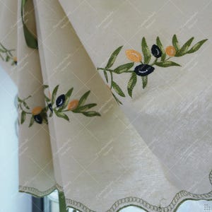 May include: Off-white linen curtain with embroidered olive branch design. The embroidery features green leaves and black and yellow olives. The curtain has a scalloped edge with green stitching, adding a decorative touch to the kitchen or dining room.