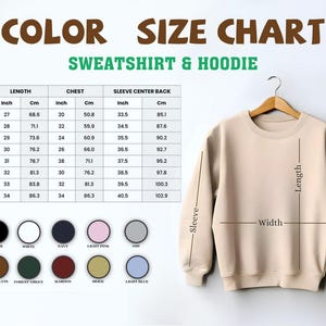Puede incluir: Una sudadera beige cuelga de una percha de madera, con medidas de largo, ancho y tama&ntilde;o de manga. Una tabla de tallas muestra medidas en cent&iacute;metros y pulgadas, junto con opciones de color como negro, blanco, azul marino y rosa claro.