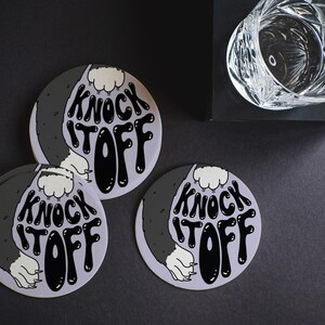 Custom design coasters are shown on a black table surface. These coasters feature a submitted, custom design.