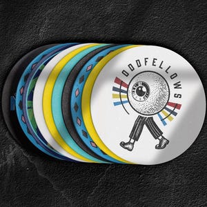 Custom design coasters featuring multiple designs are shown against a black concrete background.