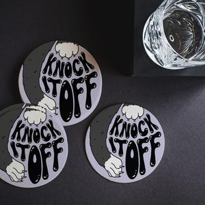 Custom design coasters are shown on a black table surface. These coasters feature a submitted, custom design.