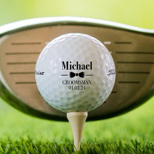 Golf ball on tee shown with Wedding Bowtie design. A golf club can be seen behind the ball.