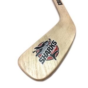 A wooden hockey stick with a logo featuring a shark on it.