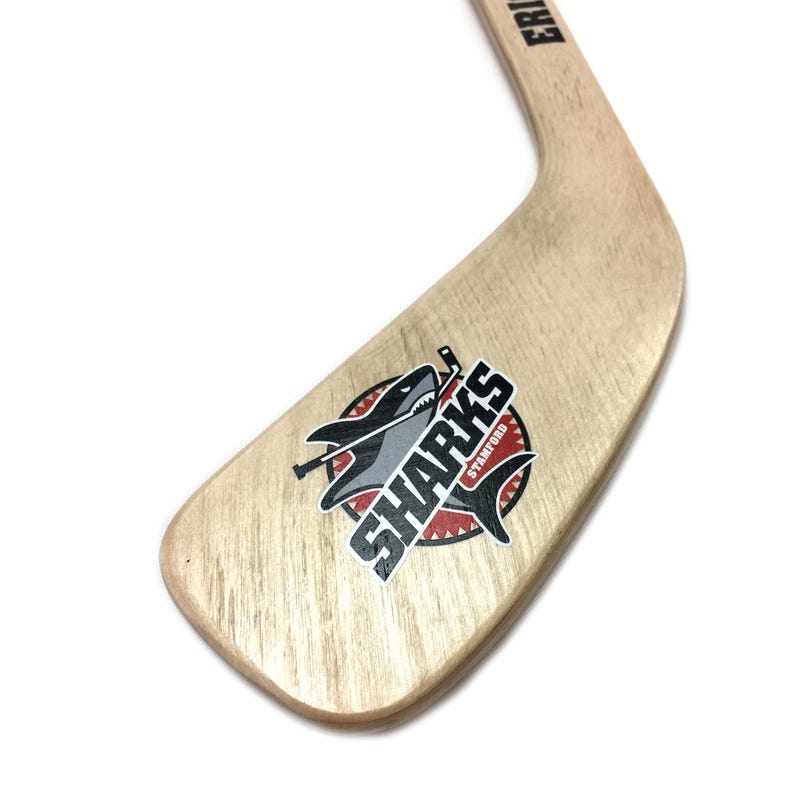 A wooden hockey stick with a logo featuring a shark on it.