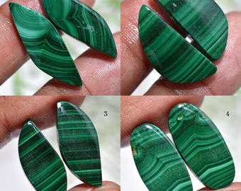 Puede incluir: Cuatro conjuntos de piedras preciosas de malaquita pulidas. Cada conjunto presenta dos piezas con diferentes formas y patrones de bandas verdes oscuras y claras. Las piedras son lisas y reflejan la luz, mostrando su belleza natural. Ideal para joyería o coleccionismo.
