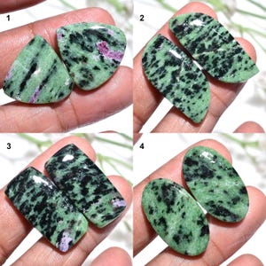 May include: Four pairs of polished zoisite gemstones. Each pair features a unique shape: triangular, curved rectangular, rectangular, and oval. The stones display a green base color with black and pink inclusions, showcasing natural patterns.