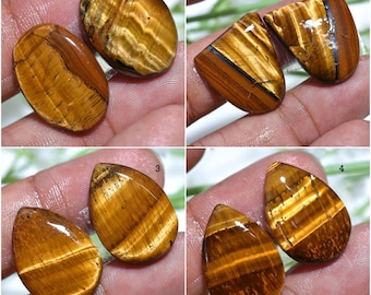 May include: Four pairs of polished tiger's eye gemstones. The stones vary in shape, including oval and teardrop. The tiger's eye exhibits a chatoyant effect with bands of golden brown and black.