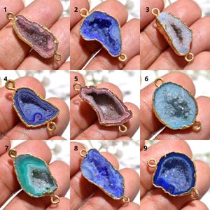 May include: Nine gemstone pendants with gold-coloured edges and loops. Each pendant showcases a unique geode design with varying colours, including pink, blue, green, and white. These pendants are suitable for jewellery making.