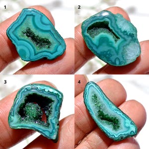 May include: Four polished agate stone slices. Each slice features concentric bands of teal and turquoise, with a dark green crystalline center. The stones vary in shape and size, showcasing natural patterns and textures.