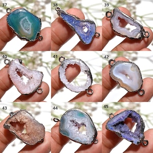 Puede incluir: Surtido de colgantes de piedras preciosas con borde de metal plateado. Los colgantes presentan una variedad de colores, incluyendo azul, morado, rosa y blanco. Cada colgante tiene un patrón único tipo geoda y dos pequeños bucles.
