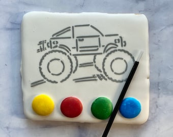 May include: A white cookie decorated with a gray outline of a monster truck, four paint dots in yellow, red, green, and blue, and a black paintbrush.