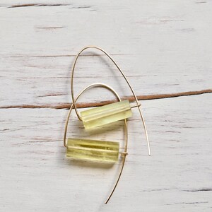 May include: A pair of gold hoop earrings with a yellow rectangular stone hanging from each hoop.