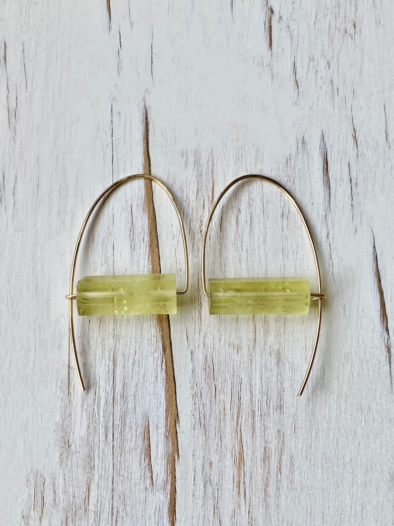 May include: A pair of gold hoop earrings with a light green stone bar in the center of each hoop.