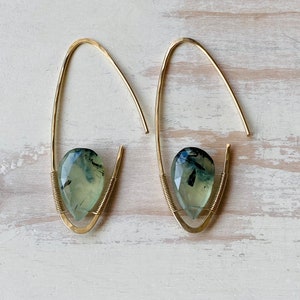 May include: A pair of gold earrings with green and black gemstone drops. The earrings are made with a simple wire design.