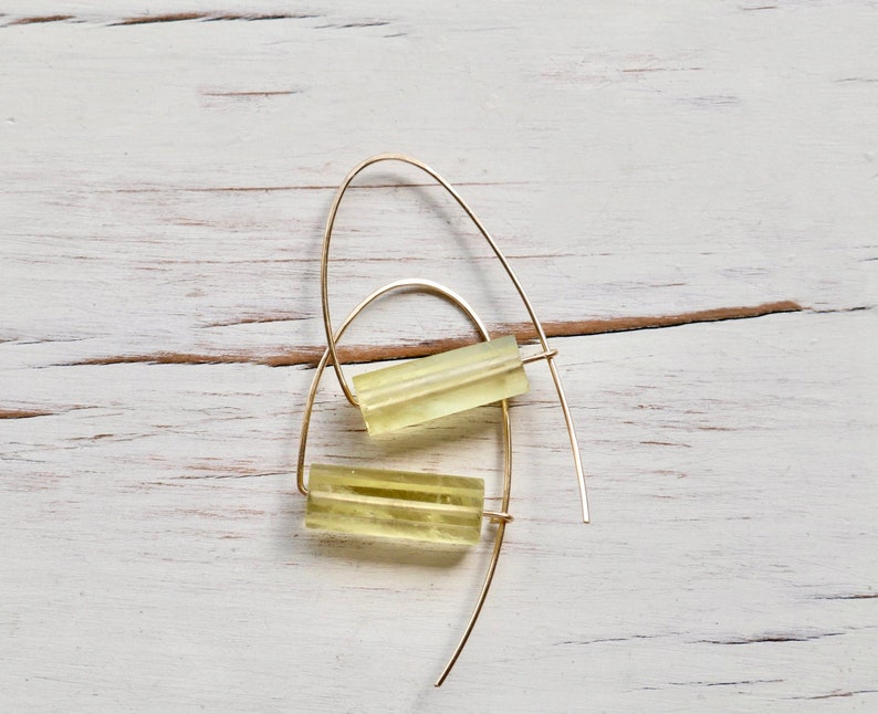 May include: A pair of gold hoop earrings with a yellow rectangular stone hanging from each hoop.