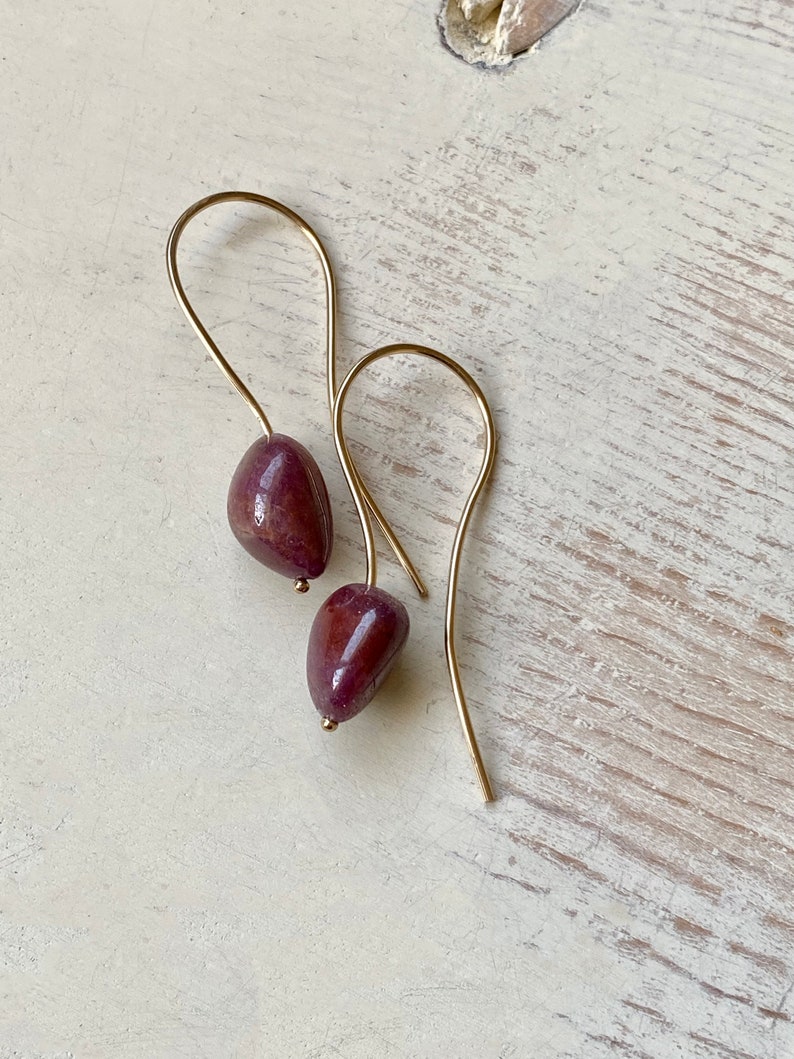 May include: A pair of gold earrings with a dark purple stone on each earring.