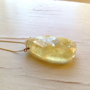 May include: A gold chain necklace with a large, faceted, yellow citrine pendant.