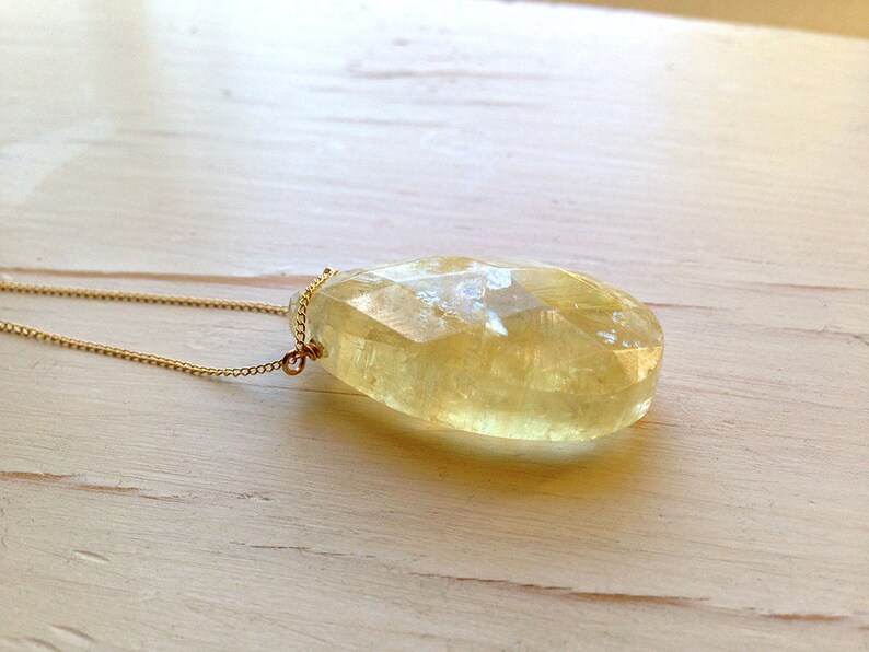 May include: A gold chain necklace with a large, faceted, yellow citrine pendant.