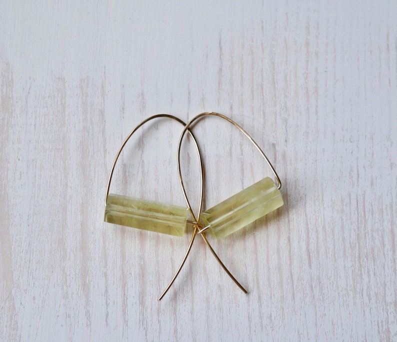 May include: A pair of gold hoop earrings with a light green rectangular stone on each hoop.