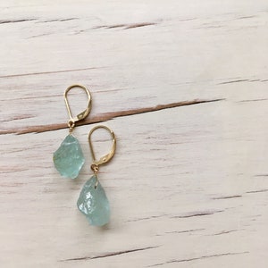 Peut inclure: Une paire de boucles d'oreilles en or avec des pierres d'aigue-marine en forme de larme bleu clair.