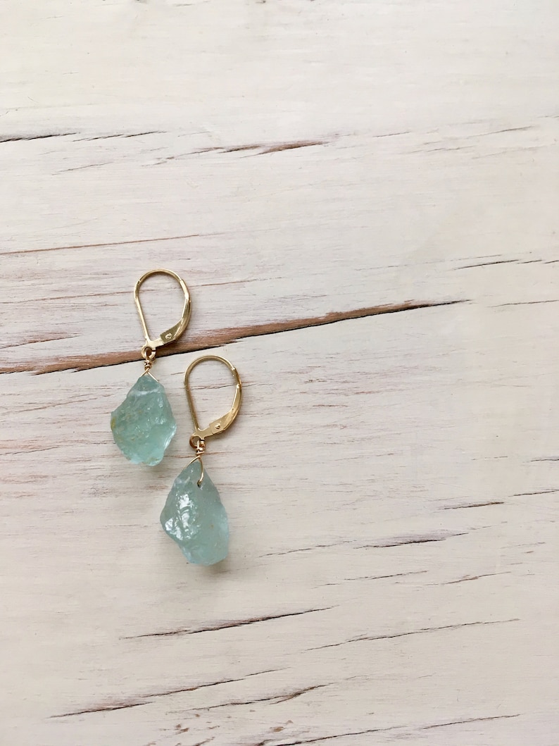 Peut inclure: Une paire de boucles d'oreilles en or avec des pierres d'aigue-marine en forme de larme bleu clair.