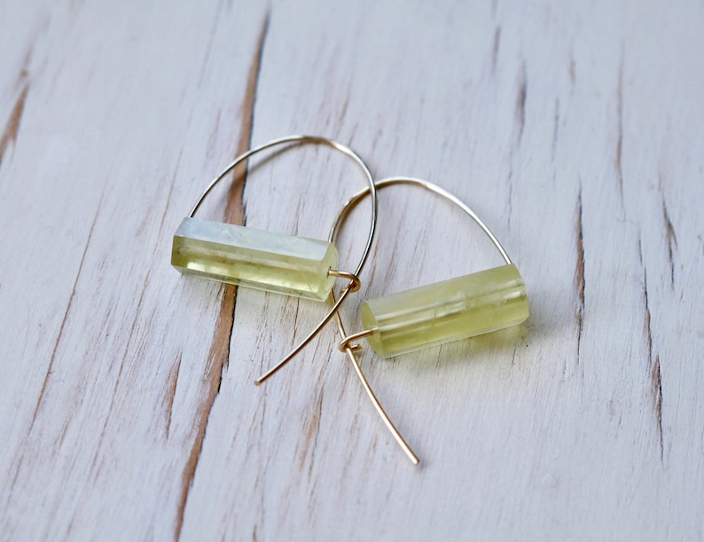 May include: A pair of gold hoop earrings with a light green rectangular stone hanging from each hoop.