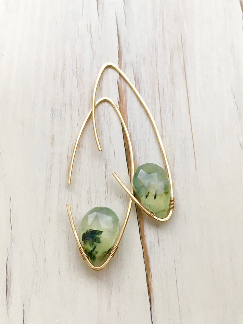 May include: Gold earrings with green and white gemstone drops. The earrings are made with a simple wire design.