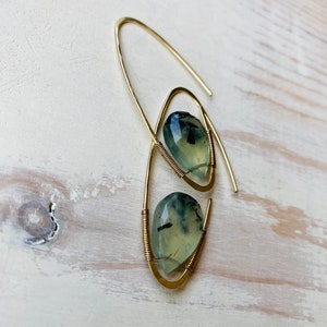 May include: A pair of gold wire earrings with green and black gemstone drops.