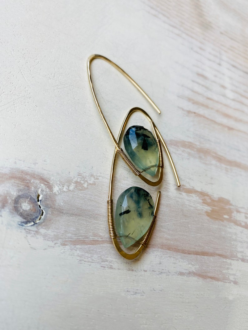 May include: A pair of gold wire earrings with green and black gemstone drops.
