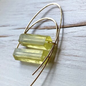 May include: Gold hoop earrings with two stacked, translucent, light yellow rectangular stones.