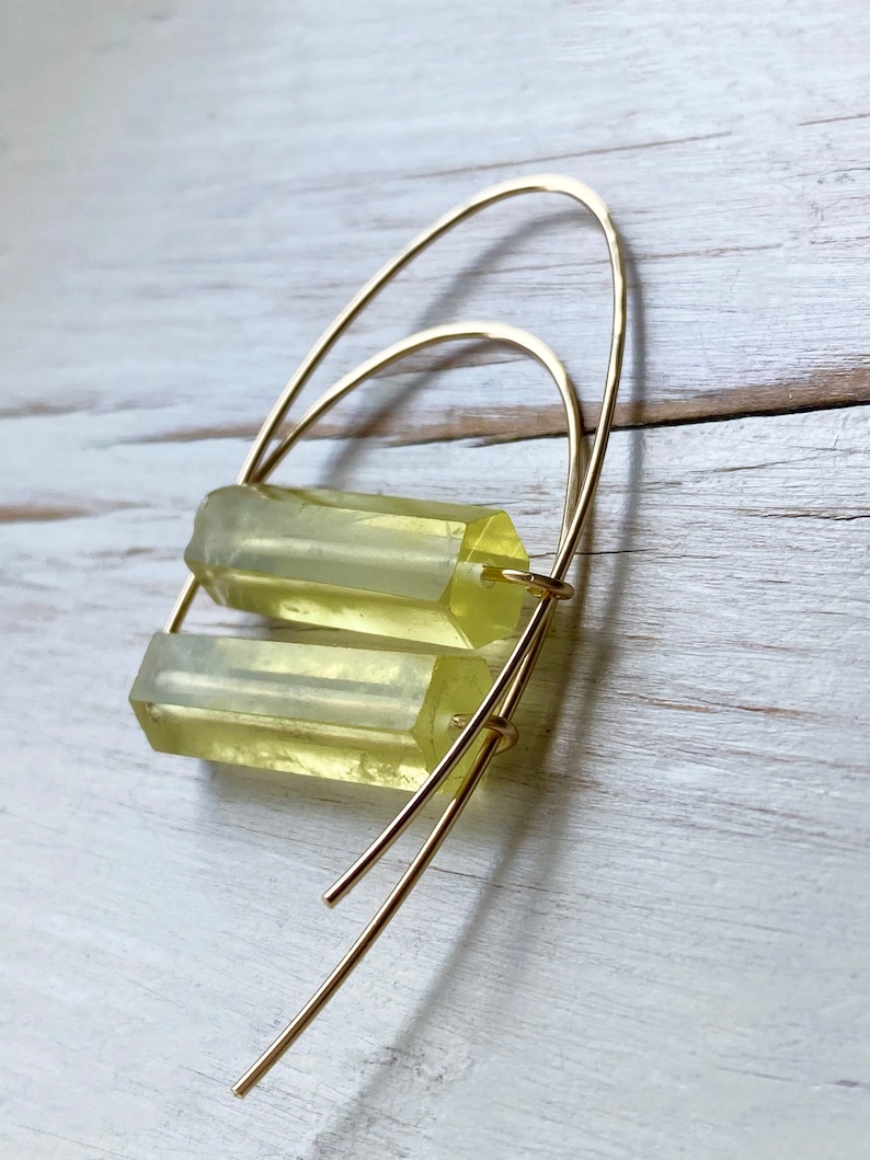 May include: Gold hoop earrings with two stacked, translucent, light yellow rectangular stones.