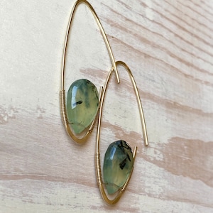 May include: Gold hoop earrings with green and black gemstone accents.