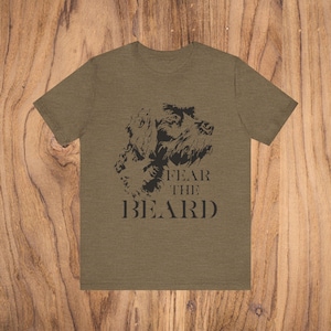 Puede incluir: Una camiseta verde con una ilustración en blanco y negro de la cabeza de un perro y el texto "FEAR THE BEARD".