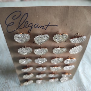 May include: A card with the word "Elegant" written on it. The card has 20 clear heart-shaped buttons with gold-colored backs.