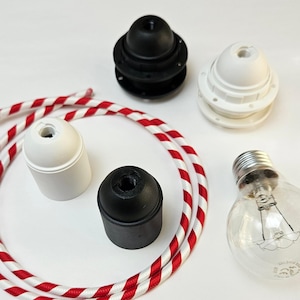 May include: A set of four black and white ceiling light fixtures with a red and white striped cord. The fixtures are made of plastic and have a screw-in base for light bulbs.