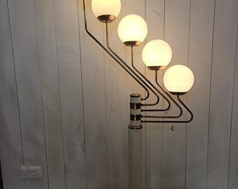 May include: A mid-century modern floor lamp with five spherical, frosted glass shades. The lamp features a white base and stem with black and gold accents, and a black metal arm structure. The lamp is designed to provide ambient lighting.
