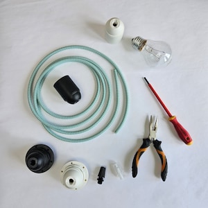 May include: A set of electrical components for a pendant light fixture, including a white cord, a black cord, a white ceramic socket, a black ceramic socket, a light bulb, a pair of pliers, and a red screwdriver.