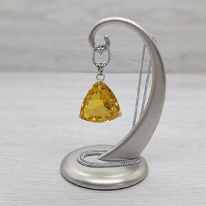 Trillion cut yellow sapphire pendant necklace front view in box, bright sunshine gemstone with faceted faces and minimal prongs, bold statement jewellery for women with sleek chain, luxury gift idea; natural internal features and reflections may be visible in closeups.
