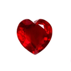 Op de afbeelding: Een facetgeslepen, hartvormige edelsteen in een diepe, rijke rode kleur. De edelsteen heeft meerdere facetten die het licht vangen en reflecteren, waardoor een sprankelend effect ontstaat. De hartvorm is symmetrisch en goed gedefinieerd.