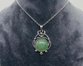 May include: Silver-toned pendant necklace featuring a round, light green stone. The pendant has an ornate, openwork design with a circular frame and decorative accents. The chain is a delicate link style, suitable for everyday wear.