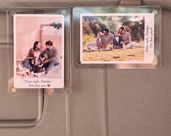 May include: Two clear acrylic photo holders attached to a car visor. Each holder contains a photograph of a family. The text "Drive safe, Daddy! We love you" is printed on each photo.