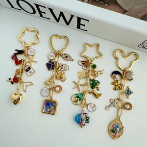 Puede incluir: Cuatro llaveros dorados con varios dijes. Cada llavero tiene una forma diferente: una estrella, un corazón, una estrella de cinco puntas y una cabeza de Mickey Mouse. Los dijes incluyen un corazón, un pez, una cruz, una concha y una flor.