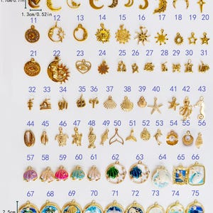 May include: A collection of 75 gold-toned metal charms arranged in rows, featuring celestial, nautical, and shell motifs. Some charms include colored enamel or faux pearls. Dimensions are indicated as 1.7cm by 1.3cm and 2.5cm by 2.5cm.