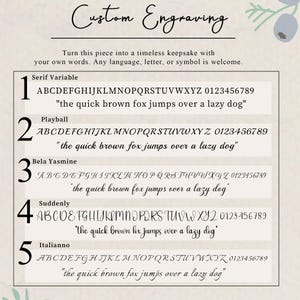May include: A custom engraving font selection chart featuring five distinct typeface options labeled Serif Variable, Playball, Bela Yasmine, Suddenly, and Italianno. Each option displays the full alphabet, numbers zero through nine, and a sample sentence.