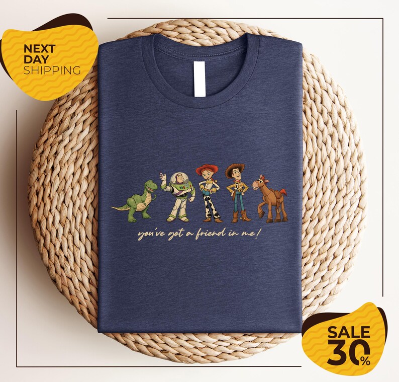 A blue t-shirt with a graphic design featuring characters from the Toy Story movie, including Woody, Buzz Lightyear, and a dinosaur. The text on the t-shirt says "you've got a friend in me!"