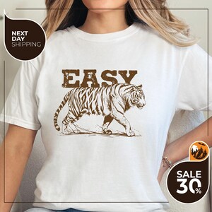 A woman wearing a white t-shirt with a graphic of a tiger and the word "EASY" printed on it.