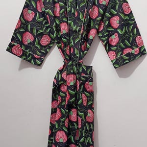 May include: A black floral print robe with pink flowers and green leaves. The robe has white trim and a tie closure. The text "UMARIA FASHION" is visible on the hanger and a tag.