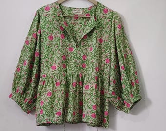 May include: A green blouse with a floral pattern of pink flowers and green leaves. The blouse has three-quarter sleeves, a v-neck, and a gathered waist. The tag reads "UMARIA FASHION".