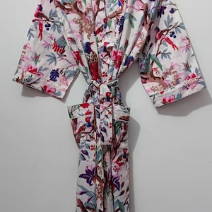 May include: White floral print robe with a tie belt. The robe features a colorful bird and floral pattern in shades of red, pink, purple, and green. The text "UMARIA FASHION" is visible on a tag.